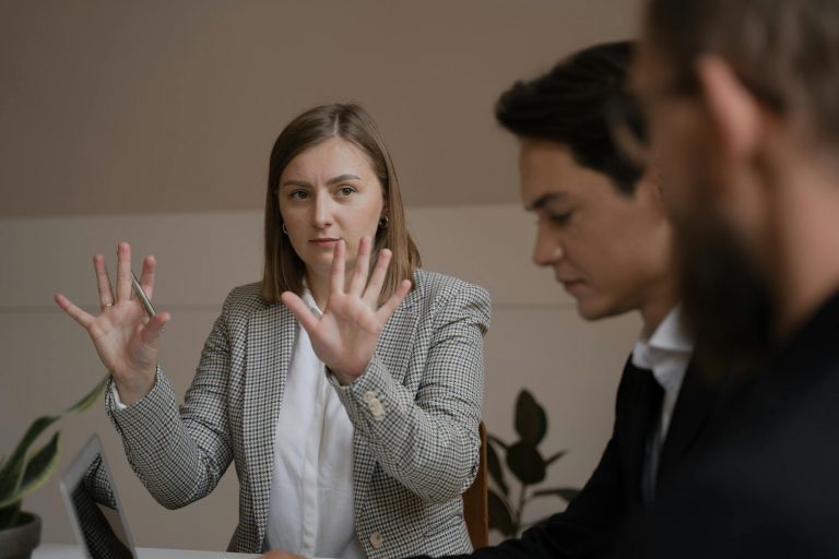 Three professionals in a meeting room engaged in a focused business discussion.